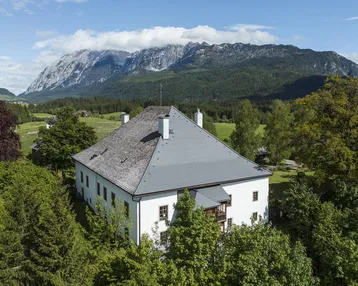 Großes Anwesen mit traditionellem Dach und beeindruckendem Bergblick in ländlicher Umgebung.