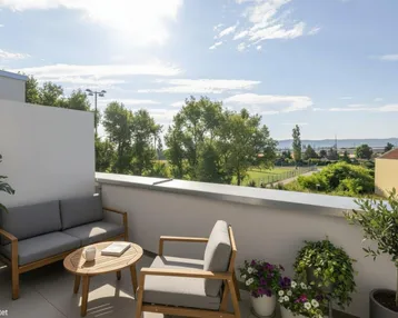 Heller Balkon mit modernen Gartenmöbeln und weitem Blick ins Grüne und auf die Landschaft.