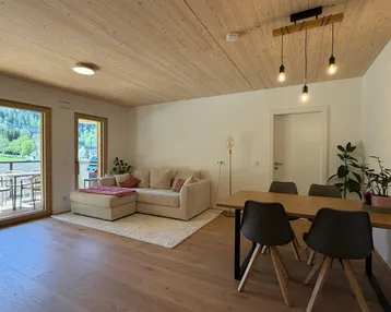 Heller offener Wohn- und Essbereich mit Holzboden, Holzdecke und Zugang zur Terrasse.