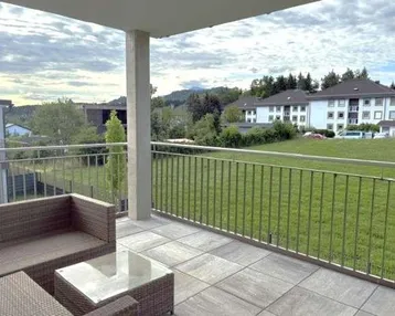 Geräumiger Balkon mit bequemen Outdoor-Möbeln und Blick ins Grüne.