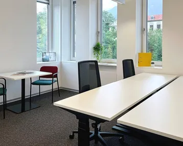 Helles Büro mit mehreren Arbeitsplätzen, großen Fenstern und einem schönen Blick ins Grüne.