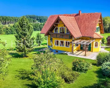 Großzügiges Einfamilienhaus mit gelber Fassade, rotem Ziegeldach und weitläufigem Garten in ländlicher Umgebung.