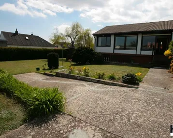 Vorderansicht des Hauses mit gepflegtem Rasen, Blumenbeeten und einem gepflasterten Weg.