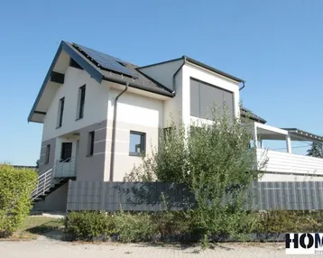 Modernes Einfamilienhaus mit Photovoltaikanlage auf dem Dach und gepflegtem Vorgarten.