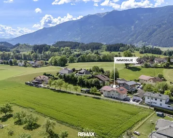 Luftaufnahme der Immobilie in ländlicher Umgebung mit Bergen im Hintergrund und grünen Feldern.
