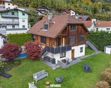 Großzügiger Gartenbereich mit Pool, Terrasse und Sitzgelegenheiten, umgeben von grüner Landschaft und Bergen.