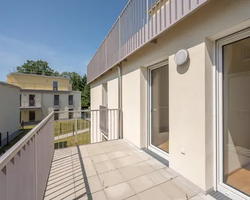 Heller Balkon mit Fliesenboden und Blick auf die umliegenden Gebäude und Grünflächen.