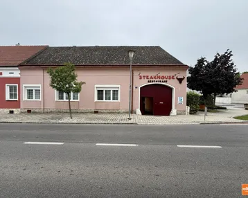 Rosa Gebäude mit "Steakhouse Restaurant" Beschriftung und einem großen Tor an der Straße.