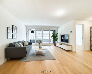 Helles und modernes Wohnzimmer mit Holzboden, bequemer Couch und Zugang zum Balkon.