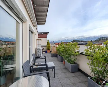 Geräumige Terrasse mit Sitzgelegenheiten, Pflanzen und herrlichem Bergblick.