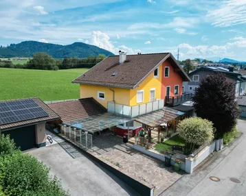 Luftaufnahme eines Einfamilienhauses mit Solaranlage, Carport und Garten in ländlicher Umgebung.