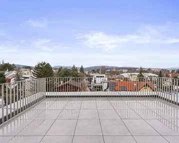 Geräumige Dachterrasse mit hellen Fliesen und weitem Blick über die Stadt und die umliegende Landschaft.
