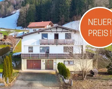 Traditionelles Haus mit Balkonen und Blick auf die verschneite Berglandschaft, mit "Neuer Preis!" Hinweis.