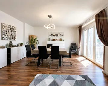 Heller Wohn- und Essbereich mit modernem Holzboden, stilvoller Einrichtung und Zugang zum Balkon.
