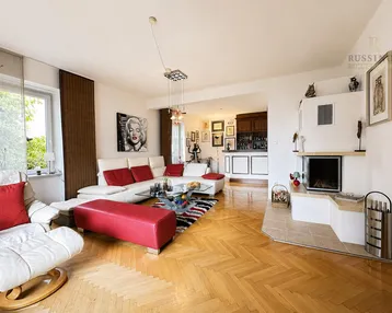 Helles Wohnzimmer mit Parkettboden, Kamin und integrierter Bar, modern eingerichtet mit roten Akzenten.