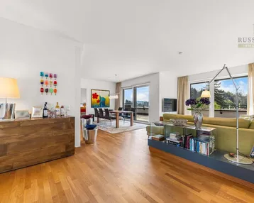 Geräumiger, offener Wohn- und Essbereich mit Holzboden und Zugang zur Dachterrasse.