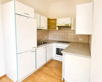Helle Einbauküche mit weißen Schränken, integrierten Geräten und Laminatboden.