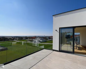 Geräumige Dachterrasse mit Glasgeländer und weitem Blick über die Landschaft und umliegende Häuser.