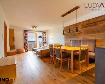 Geräumiger Wohn-Essbereich mit Holzboden, gemütlicher Sitzecke und Zugang zum Balkon.