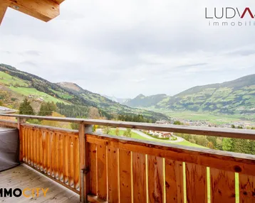 Großer Holzbalkon mit atemberaubendem Blick auf die umliegende Berglandschaft und das Tal.