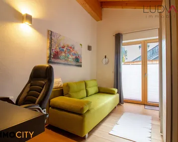 Helles Zimmer mit Schreibtisch, Sofa und Zugang zu einem französischen Balkon.