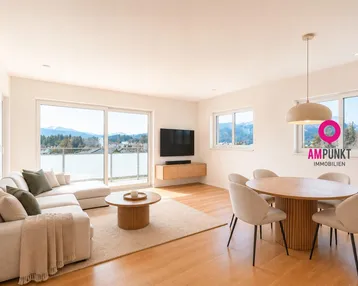 Helles Wohn-Esszimmer mit Holzboden, bequemer Couch und Esstisch, bietet Zugang zum Balkon und Bergblick.