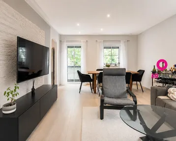 Helles Wohn- und Esszimmer mit modernem Design, Holzboden und dekorativer Steinwand.