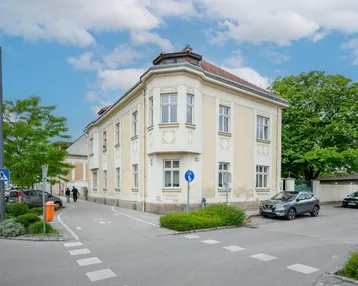 Historisches Eckgebäude mit klassischer Fassade und vielen Fenstern an einer städtischen Kreuzung.