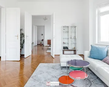 Helles Wohnzimmer mit Fischgrätparkett, hohen Decken und modernen Möbeln in einem Altbau.