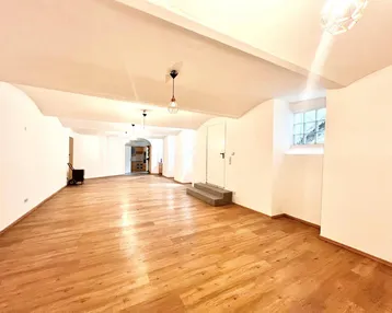 Geräumiger, heller Raum mit Holzboden und gewölbter Decke, ideal für vielseitige Nutzung.