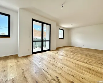 Helles, leeres Wohnzimmer mit Holzboden und Zugang zum Balkon, ideal für individuelle Gestaltung.