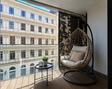 Gemütlicher Balkon mit Hängesessel und Blick auf die historische Stadtarchitektur.
