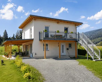 Modernes Einfamilienhaus mit Balkon, überdachter Terrasse und Bergblick in ländlicher Umgebung.