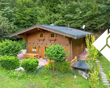 Charmantes Holzhaus im Chalet-Stil mit gepflasterter Terrasse und umgebender Natur.