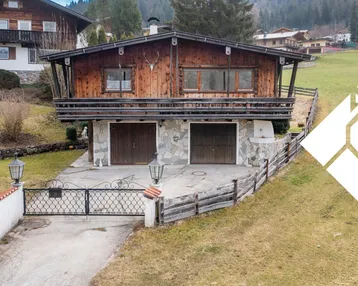 Traditionelles Holzchalet mit zwei Garagen und Einfahrt in alpiner Umgebung.