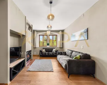 Helles Wohnzimmer mit Holzboden, Kamin und bequemen Sofas für entspannte Abende.