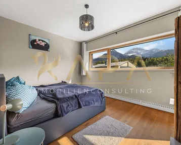 Gemütliches Schlafzimmer mit Holzboden und großem Fenster mit Bergblick.
