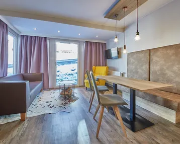 Heller Wohnbereich mit bequemer Couch, Esstisch und großen Fenstern mit Blick nach draußen.