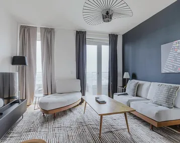 Modernes Wohnzimmer mit bequemen Möbeln, Holzboden und Zugang zum Balkon.