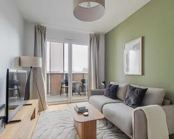 Helles Wohnzimmer mit modernem Sofa, Holzboden und Zugang zu einem Balkon.