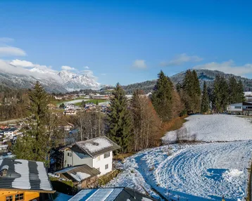 Panoramablick auf verschneite Häuser und majestätische Berge unter blauem Himmel.