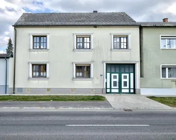 Fassade eines Wohnhauses mit Garage und Fenstern, direkt an einer Straße gelegen.