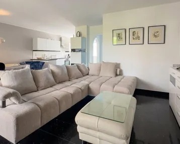 Geräumiger offener Wohnbereich mit beigem Ecksofa, modernem TV-Möbel und Blick auf den Essbereich.