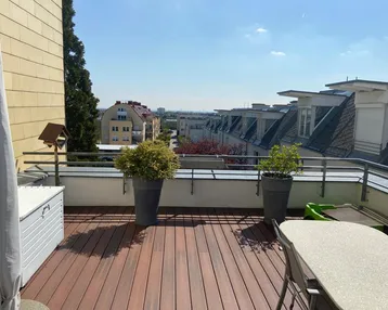Große Dachterrasse mit Holzboden, Pflanzen und weitem Blick über die Stadt.