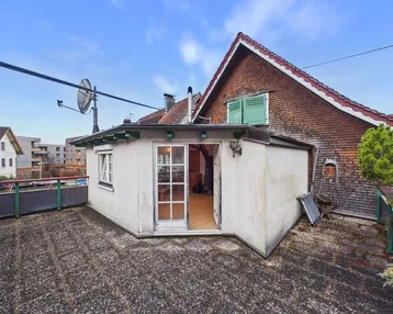 Dachterrasse mit kleinem Anbau und Blick auf die umliegende Bebauung.
