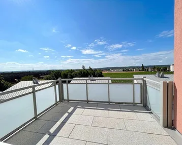 Geräumige Sonnenterrasse mit Fliesenboden und weitem Blick über die umliegende Landschaft.