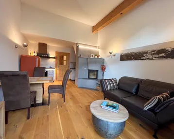 Heller offener Wohn-Essbereich mit Holzboden, Kamin und integrierter Küche.