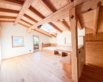 Helles Zimmer mit Holzbalkendecke, Dachfenster und Holzboden, ideal als Wohn- oder Schlafbereich.