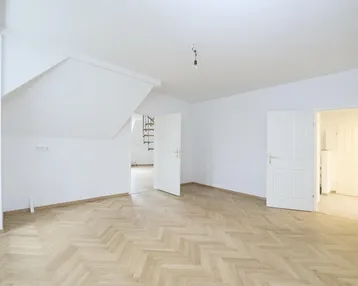 Helles Zimmer mit Fischgrätparkettboden, weißen Wänden und Dachschrägen, bereit zur individuellen Gestaltung.