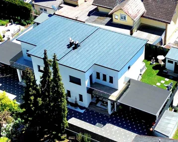 Luftaufnahme eines modernen Einfamilienhauses mit Flachdach und gepflegtem Gartenbereich.
